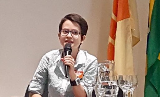 Beatriz Souza falando ao microfone em uma palestra